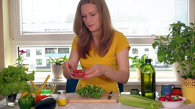 孕妇坐在厨房桌旁吃小番茄蔬菜视频素材