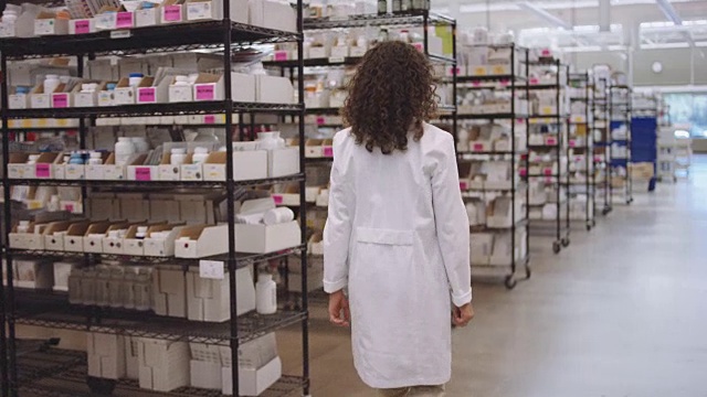 4K超高清:年轻女性药剂师走过一排排药物视频下载
