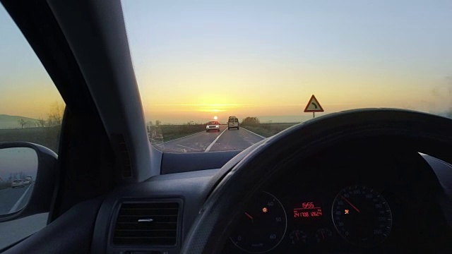 司机的手放在方向盘上，驶向日落的地平线视频素材