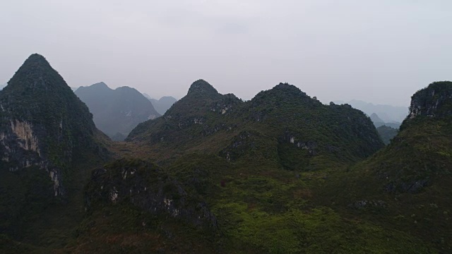 航拍:飞越悬崖和喀斯特丘陵。在中国桂林阳寿县，五颜六色的山被雾或雾霾所覆盖。视频素材