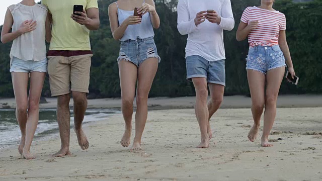 人们用手机在热带海滩上行走，游客团体在线交流视频素材