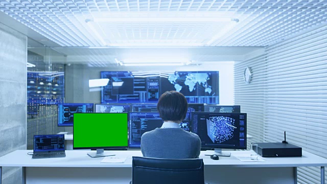 IT技术人员在他的个人电脑上工作与神经网络与绿屏模型的后视图。他在一个有多个显示器显示图形的大系统控制数据中心工作。视频素材
