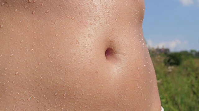 一个晒黑的女性腹部的特写，湿漉漉的液滴视频下载