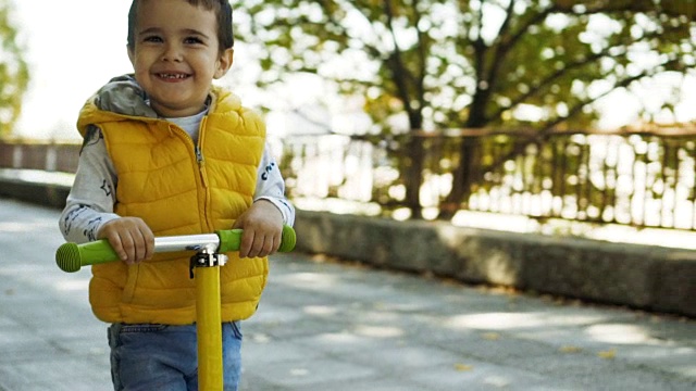 蹒跚学步的小男孩骑滑板车视频素材