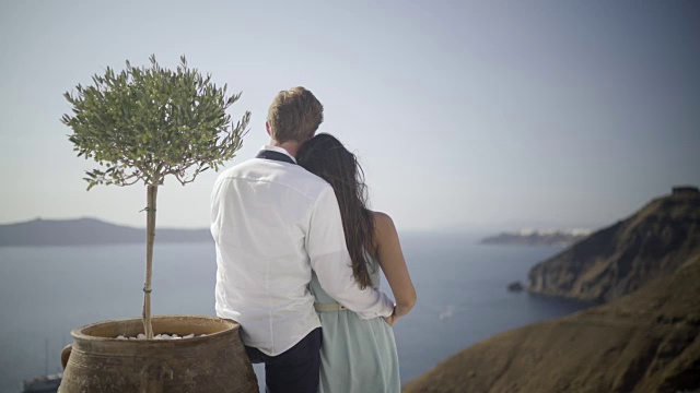 在圣托里尼岛的一棵小橄榄树旁，一对浪漫的情侣视频素材