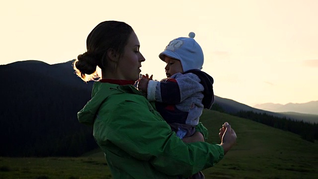 在山中的夕阳背景下，一个女人抱着婴儿视频素材
