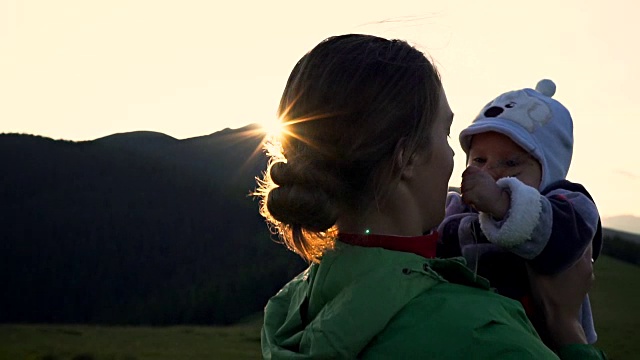 在山中的夕阳背景下，一个女人抱着婴儿视频素材
