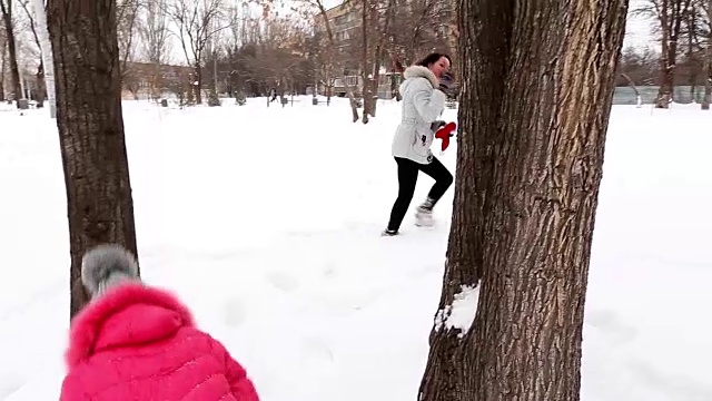 两个女孩，母亲和女儿，在冬天霜冻的一天在公园扔雪。视频素材