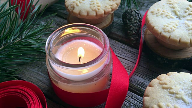 特写燃烧的白色蜡烛和圣诞肉馅饼在质朴的木头桌子上。概念的冬季假期和圣诞烘焙。视频素材