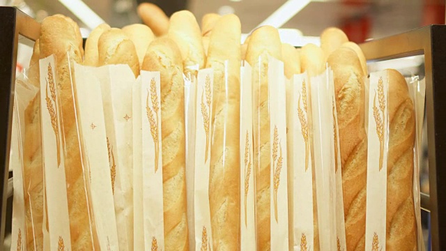 面包房柜台上一堆新鲜出炉的法式长棍面包。商店橱窗上新鲜可口的面包视频下载