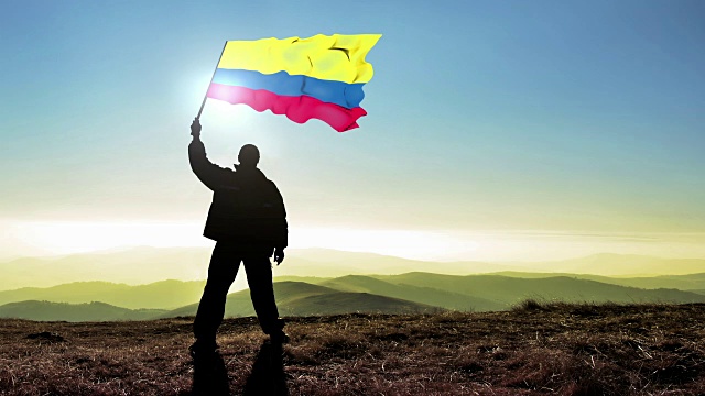 成功的剪影男子冠军在山顶挥舞哥伦比亚国旗。Cinemagraph循环背景视频下载