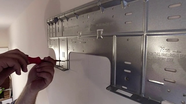 工人用螺丝刀手动拧紧安装在墙上的空调金属支架上的螺钉视频下载