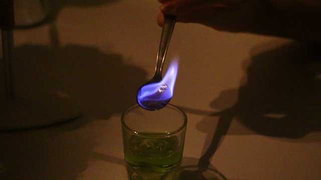 一个男人在准备苦艾酒的鸡尾酒。糖用浓饮料蘸湿，用茶匙加热即可燃烧。视频下载