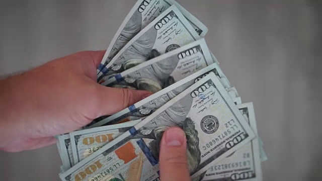 近距离观察一个数100美元钞票的男人视频素材
