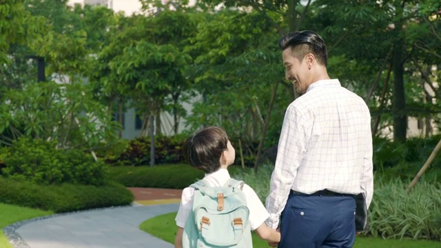 亚洲父子并排上学的后视图慢镜头视频素材