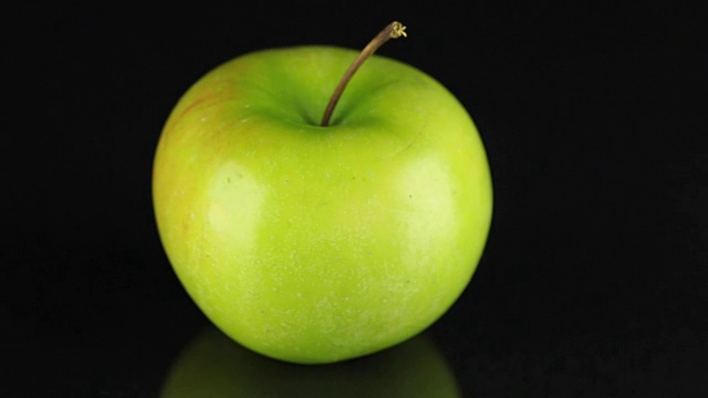 在黑色背景上旋转绿苹果。水果视频素材