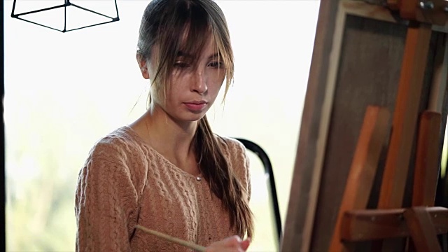 灵感的年轻女子画家正在工作的一幅画在美术工作室在白天的时间视频下载