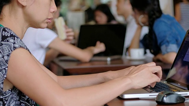 年轻女性在咖啡店使用笔记本电脑。视频下载