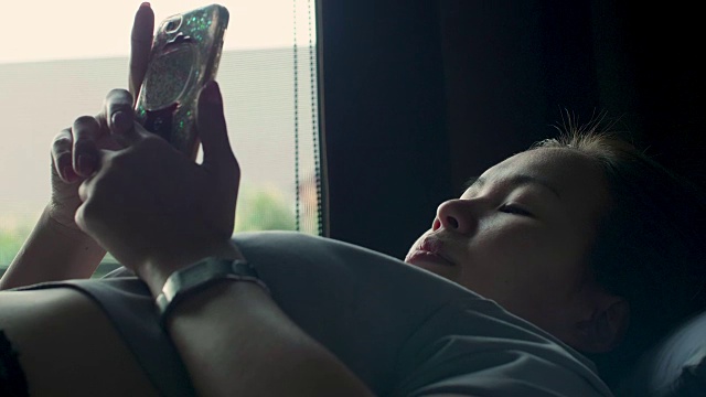 女人在床上使用手机视频下载