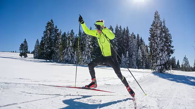在一个阳光明媚的冬日里，越野滑雪者全功率滑冰上山滑雪视频下载