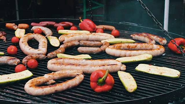 不同的香肠在巨大的烤架上和蔬菜一起烤。美食节视频素材