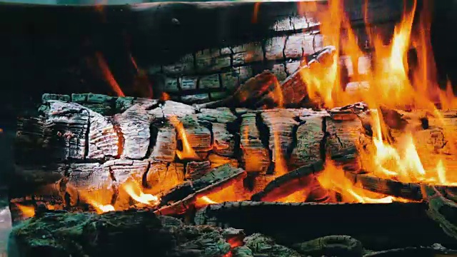 近距离观看一个巨大的燃烧的柴火或原木躺在绿色和燃烧的火焰在露天视频素材