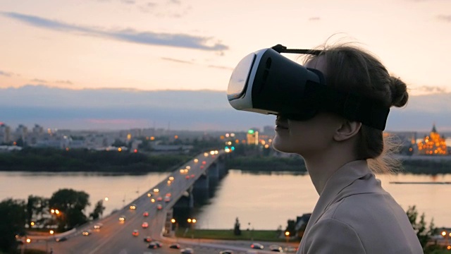 一名女子在日落后佩戴虚拟现实眼镜视频素材