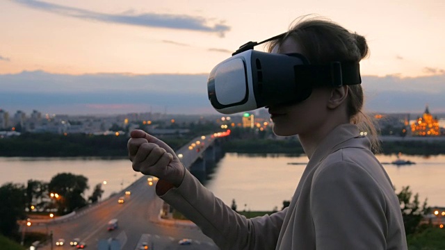 一名女子在日落后佩戴虚拟现实眼镜视频素材