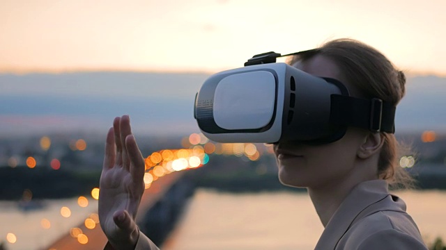 一名女子在日落后佩戴虚拟现实眼镜视频下载