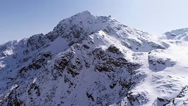 空中飞行向前移动，越过雪峰山脊建立。冬季户外雪高山野自然景观。4k无人机飞行建立镜头视频素材