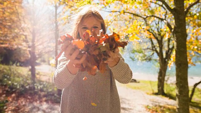 快乐的女人在湖边抛五颜六色的秋叶视频下载