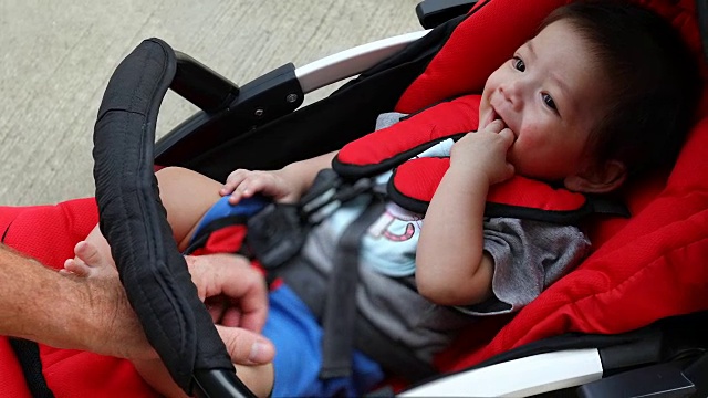 可爱的小男孩开心地笑在婴儿车的座位上视频素材