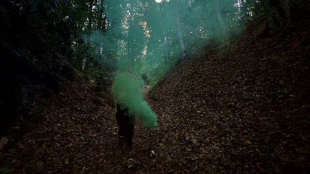 人在森林中持有绿色烟雾- 4K分辨率视频下载