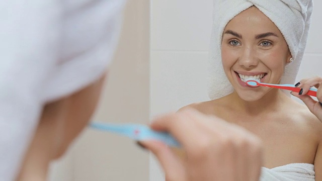 一个头裹毛巾的漂亮女人在浴室的镜子前刷牙视频素材