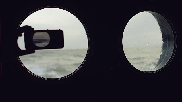 在波涛汹涌的海面上，一个人在一艘船的舷窗旁视频素材