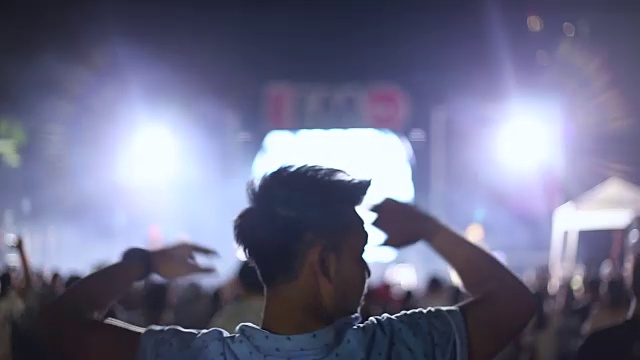 从后面看，一个男人和一群人在户外音乐会中跳舞视频素材