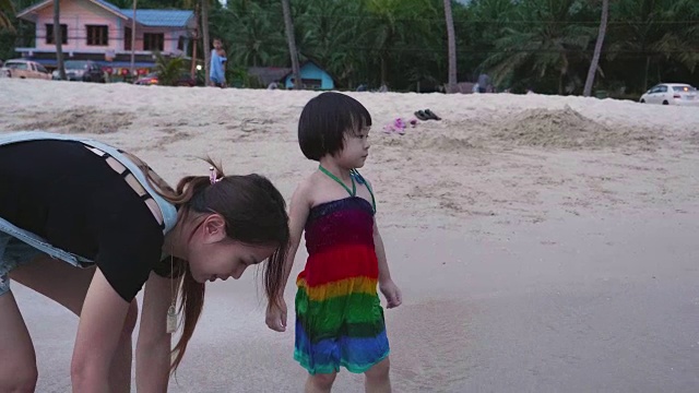 年轻的母亲和女儿手牵着手走在海滩上视频下载