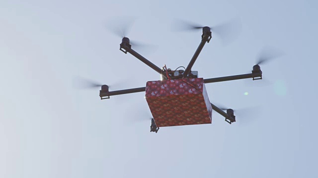 LENS FLARE:无人机无人机交付。多直升机飞大红色的礼物在蓝天视频下载