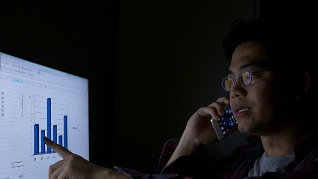 亚洲男人打电话和工作笔记本电脑在晚上视频素材