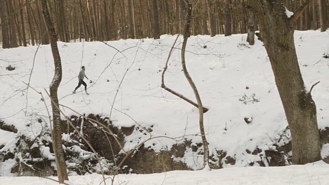 一个肌肉发达的男人在树林里的雪地上奔跑视频素材