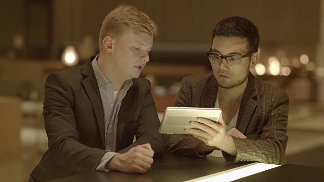 两位企业家用数字平板电脑谈生意。在公共场所会面。亚洲和高加索人。视频素材