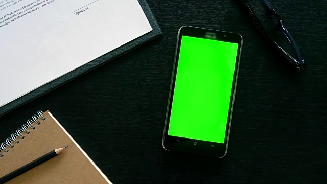 男人用手用手机用绿色屏幕在办公室桌面上查看视频素材