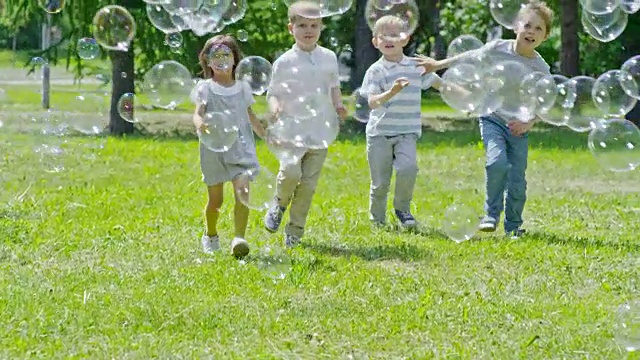 快乐的孩子们在许多肥皂泡中奔跑视频下载