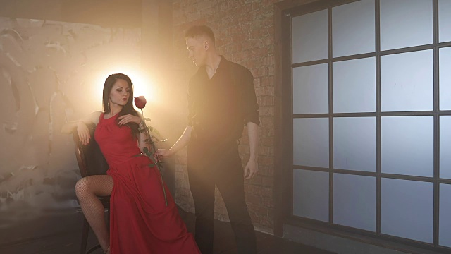 一个难以接近的女人从一个富有的男人手里接过一朵红玫瑰。视频下载