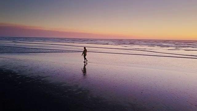 日落时分独自在海滩上行走的女人-无人机拍摄视频素材