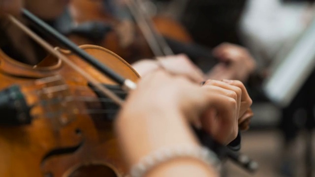 交响乐会上，一个男人在拉大提琴，手拉近了视频素材
