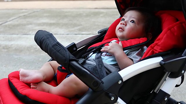 可爱的小男孩开心地笑在婴儿车的座位上视频素材