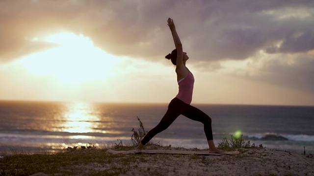 美丽的中年妇女在海滩上练习瑜伽日落在大西洋在法国南部。视频素材