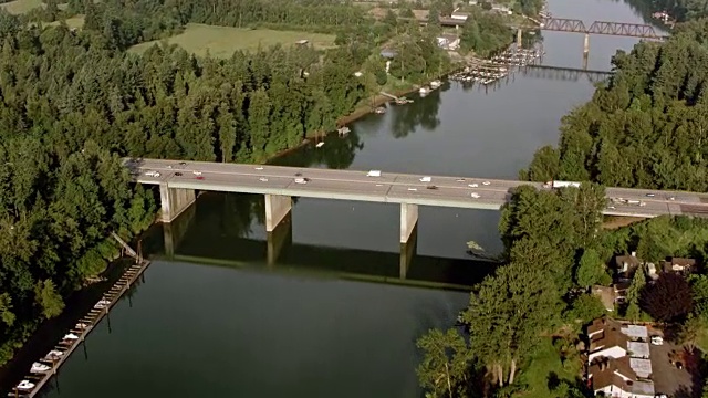 阳光下，汽车在河上的桥上行驶视频素材