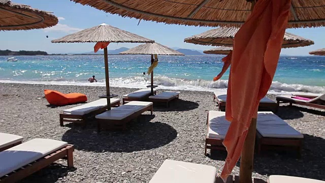 豪华时尚的躺椅，带伞的日光浴床，在沙滩上放松视频素材